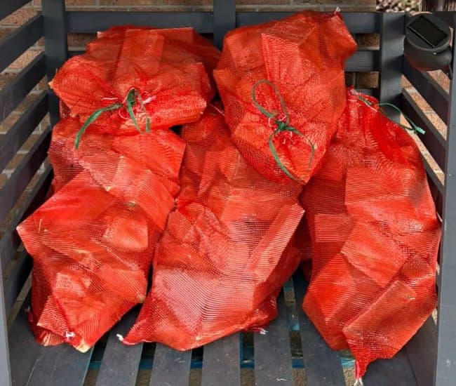Red net bags filled with split firewood logs